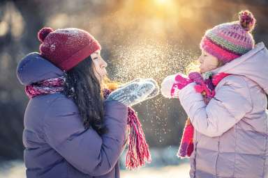 Mother and daughter playing in winter park