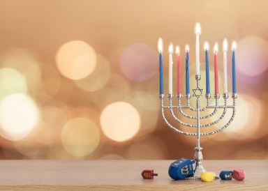 Hanukkah Jewish holiday background with menorah (Judaism candelabra)  burning candles and traditional Dreidrel game toy on wood table and on autumn bokeh sun flare