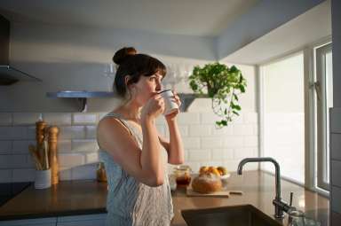 Woman drinking from mug in zero waste kitchen.