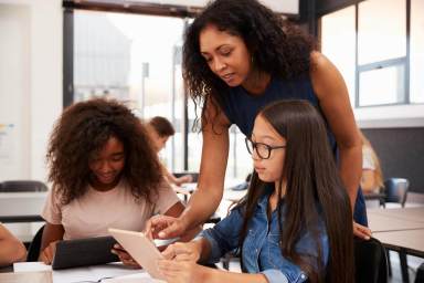 Teacher helping high school students with technology