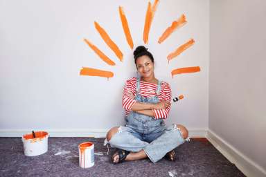 Woman with brush strokes on wall renovating home