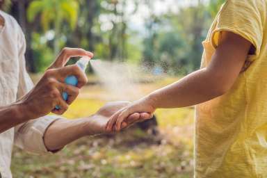 dad and son use mosquito spray.Spraying insect repellent on skin outdoor